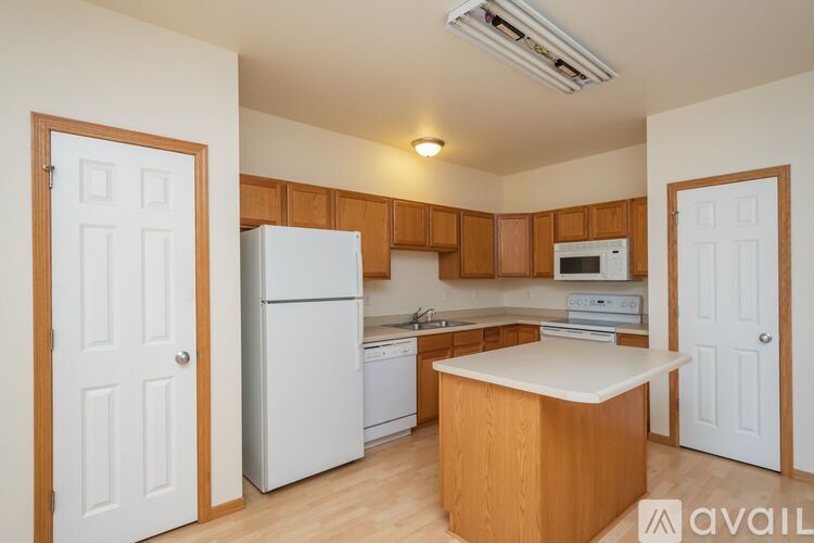 A kitchen with white appliances and wooden cabinets.
