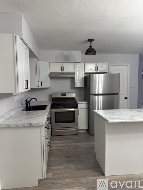 A kitchen with white cabinets and a marble countertop.