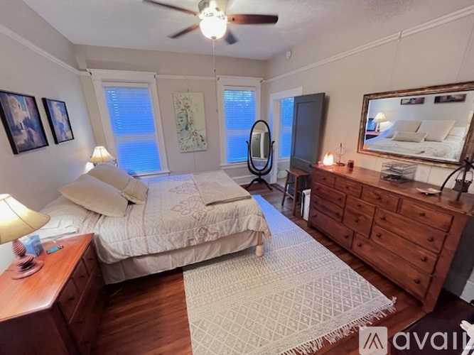 A bedroom with a bed, dresser, and ceiling fan.