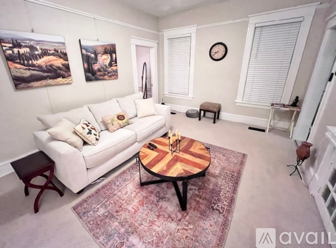 A living room with a white couch, a wooden coffee table, and a rug.