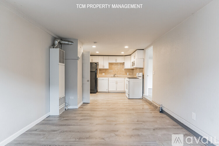 A spacious, empty room with a kitchen area in the background.