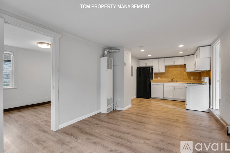 A room with a kitchen area in the background and a text that says "TCM PROPERTY MANAGEMENT".
