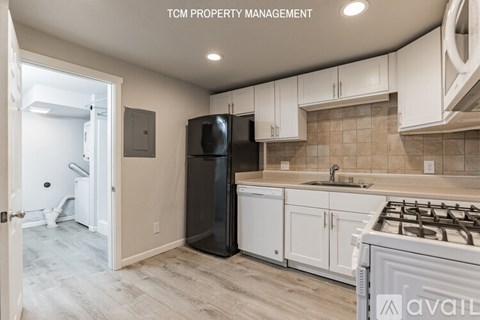 A kitchen with a black refrigerator and white cabinets.