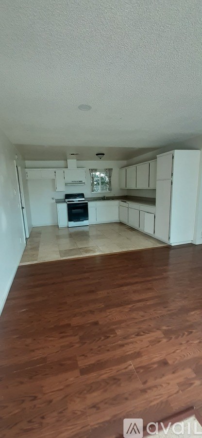 A kitchen with white cabinets and a wooden floor.