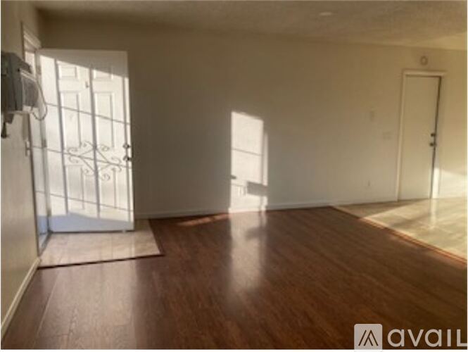 A room with wooden flooring and a door on the right.
