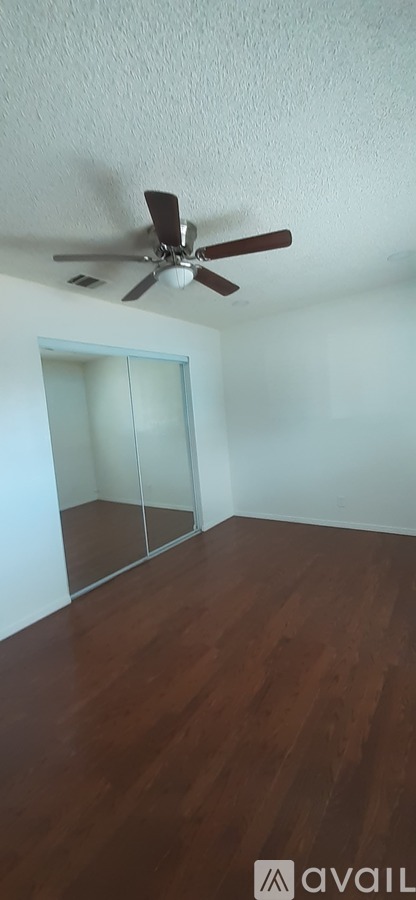 A room with a ceiling fan and wooden flooring.