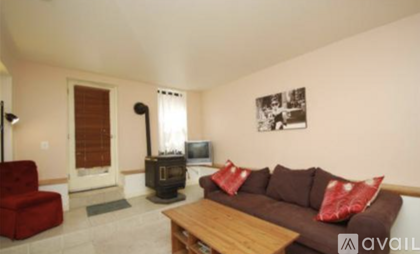 A living room with a red chair, a brown couch, and a fireplace.