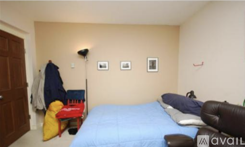A bedroom with a blue bed and a red chair.