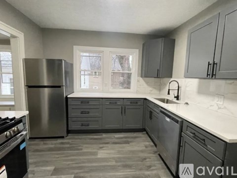 A kitchen with a stainless steel refrigerator, sink, and cabinets.