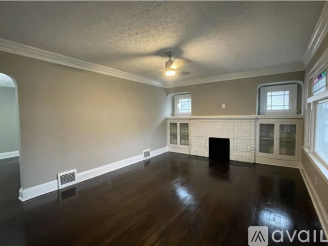 A room with a dark wood floor and a white fireplace.