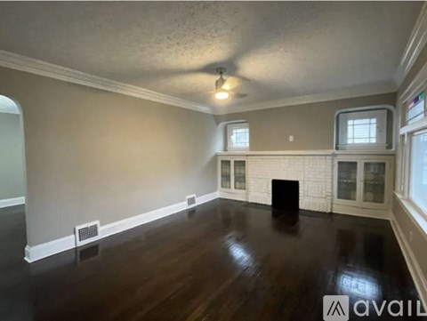 A room with a dark wood floor and a white fireplace.
