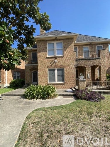 A house with a front yard and a tree branch hanging over the sidewalk.