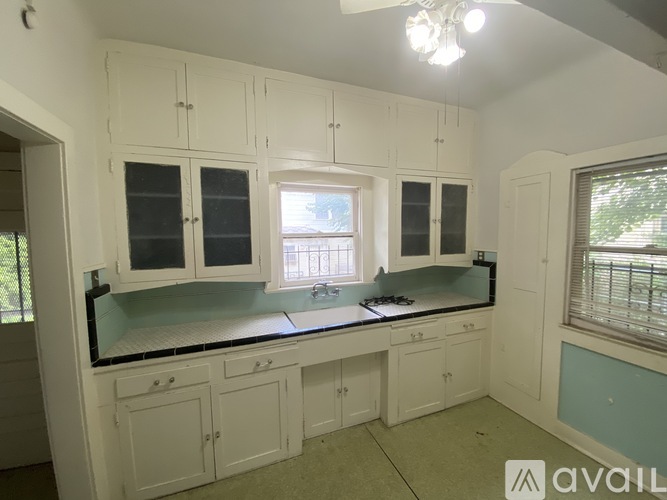 A kitchen with white cabinets and a black countertop.