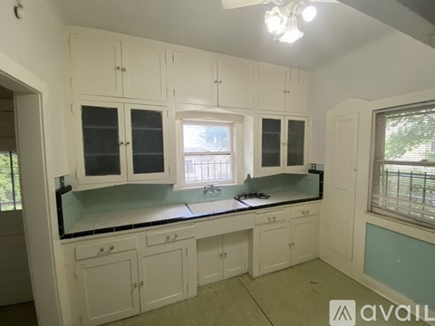 A kitchen with white cabinets and a black countertop.