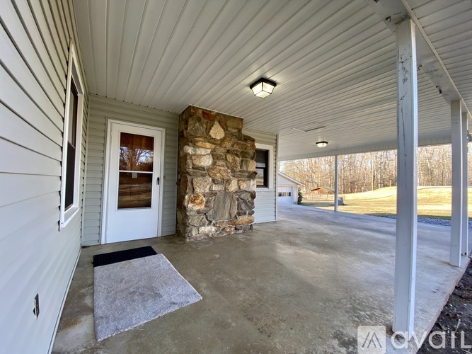 A covered porch with a stone pillar and a white door.