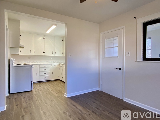 A kitchen with white cabinets and a white fridge is shown.