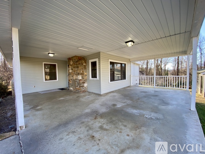 A covered porch area with a stone pillar and a concrete floor.