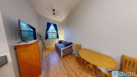 A room with a wooden table and chairs, a sofa, and a television.