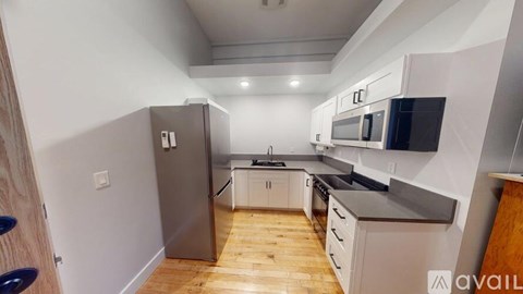 A kitchen with a refrigerator, microwave, oven, and stove top.