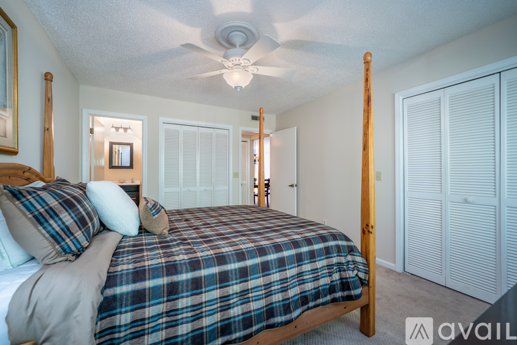 A bedroom with a bed, pillows, and a ceiling fan.