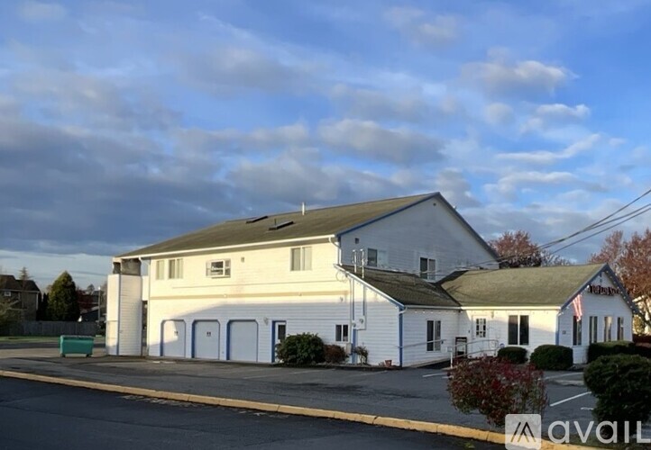 A white building with a green roof and a sign that says "available" on the front.
