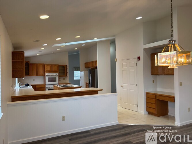 A well-lit kitchen with wooden cabinets and a hanging light fixture.