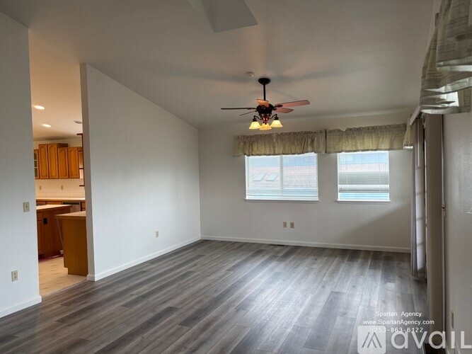 A spacious room with a ceiling fan and wooden flooring.