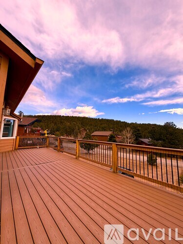 A wooden deck with a railing and a view of the sky and trees.