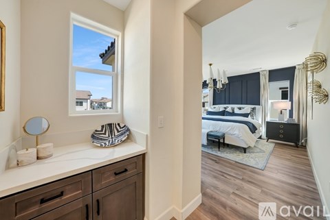 A bedroom with a large bed and a window overlooking a house.