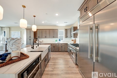 A modern kitchen with a stainless steel refrigerator and wooden floors.