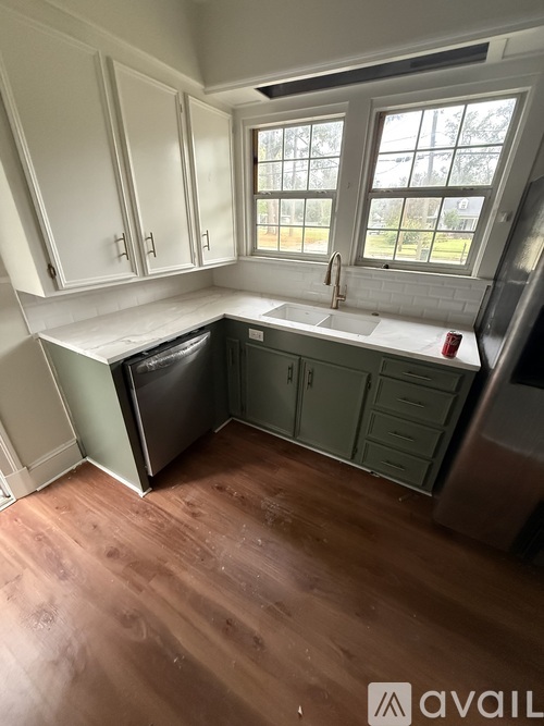 A kitchen with white cabinets and a window.