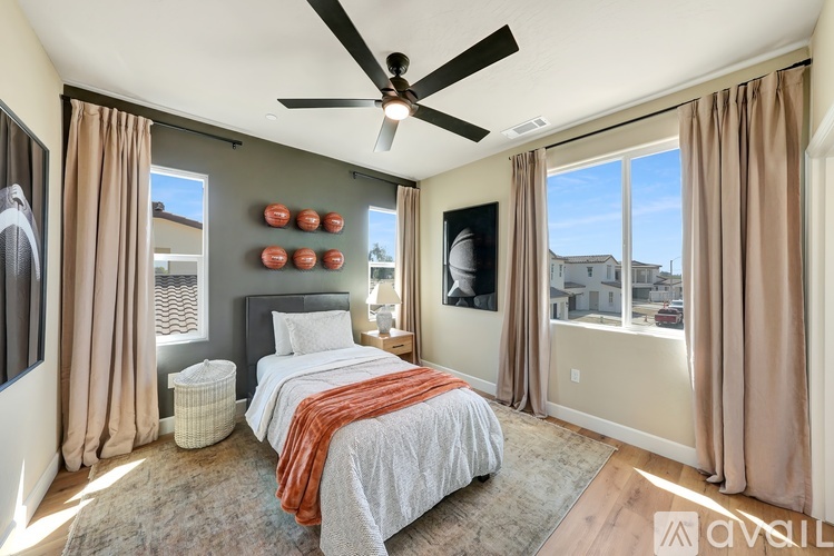 A bedroom with a bed, a ceiling fan, and a window with curtains.