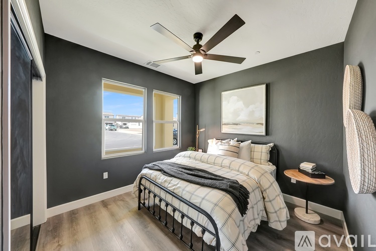 A bedroom with a bed, a ceiling fan, and a chair.