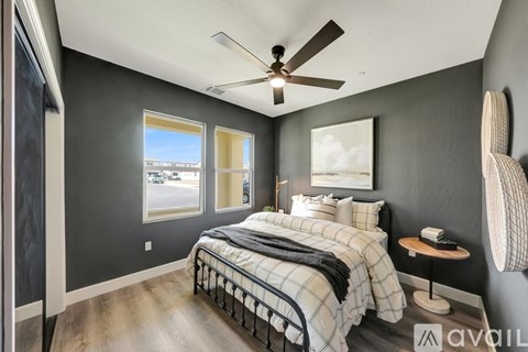A bedroom with a bed, a ceiling fan, and a chair.