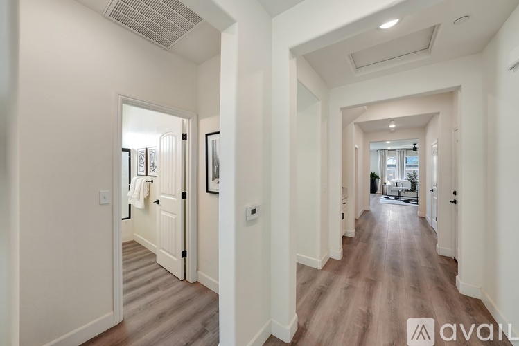 A long hallway with a door on the left and a view of a living room on the right.