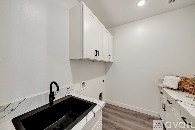 A kitchen with white cabinets and a black sink.