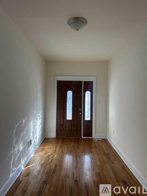 A room with wooden floors and a door leading to another room.