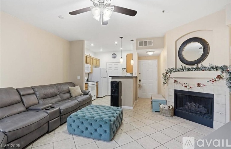A living room with a grey sofa and a fireplace with a wreath on it.