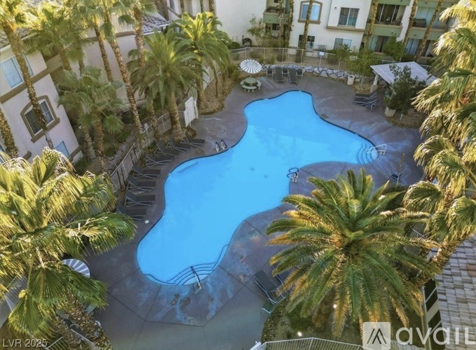 A pool surrounded by palm trees and a building in the background.