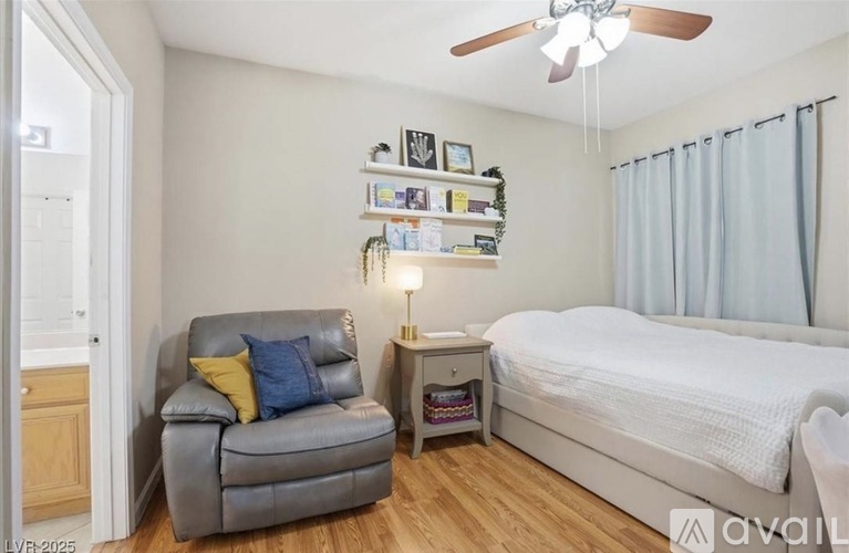 A bedroom with a bed, a chair, and a shelf with decorations.