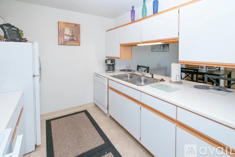 A kitchen with white cabinets and a black mat on the floor.