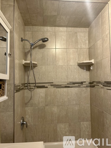 A shower area with a glass door and a wall-mounted shower head.