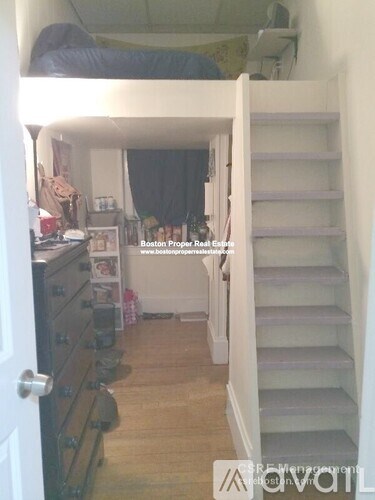 A room with a staircase and a bed in the background.