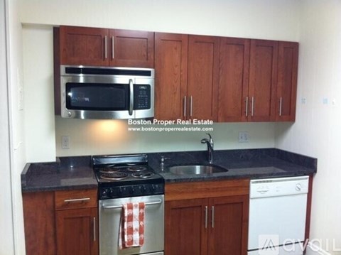 A kitchen with wooden cabinets and a black counter top.