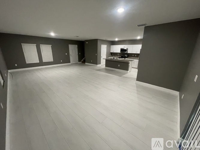 A spacious room with a kitchen area in the background.