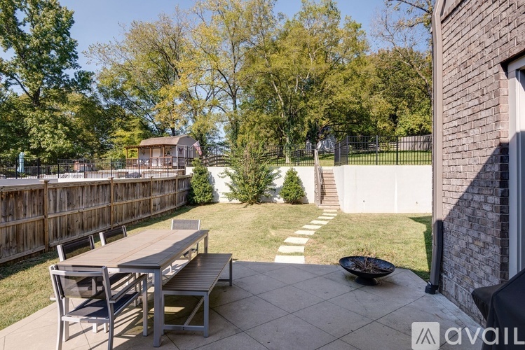 A patio with a table and chairs is surrounded by a fence and trees.