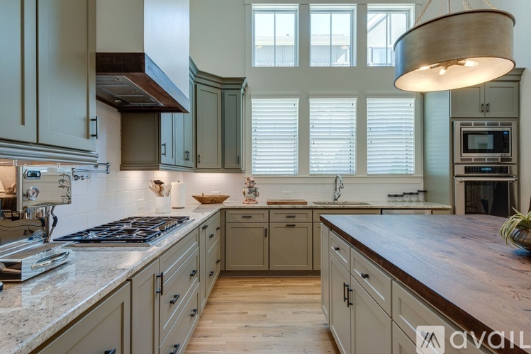 A kitchen with a wooden counter top and grey cabinets.