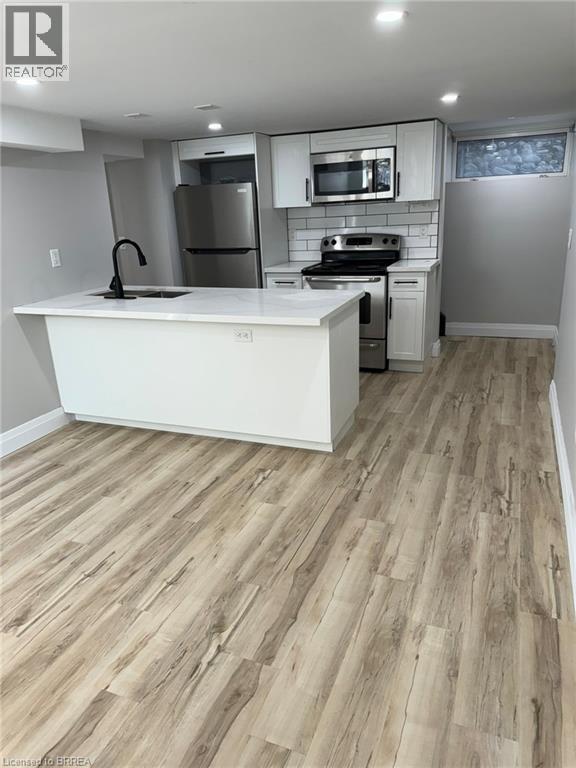 A kitchen with a white counter top and wooden flooring.