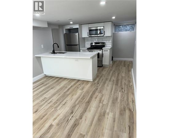 A kitchen with a white counter top and wooden flooring.