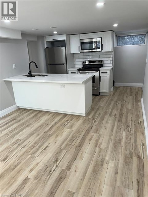A kitchen with a white counter top and wooden flooring.